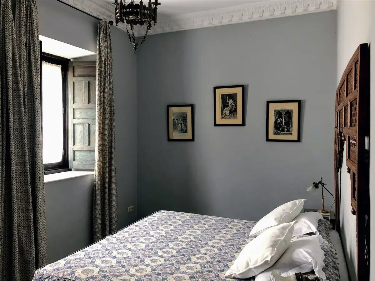 Guest room with antique wooden headboard and shuttered window